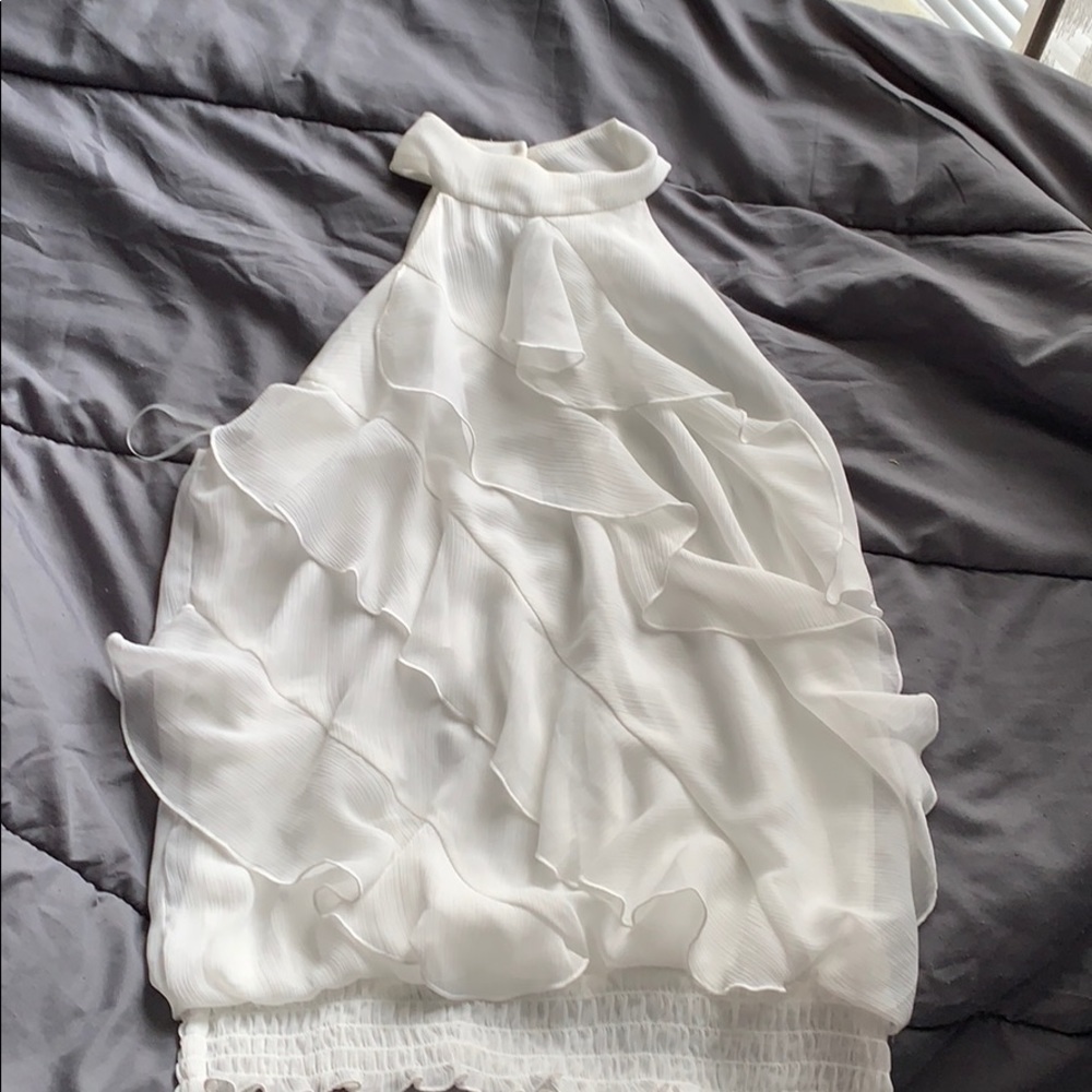 Sleeveless white top. High neck.